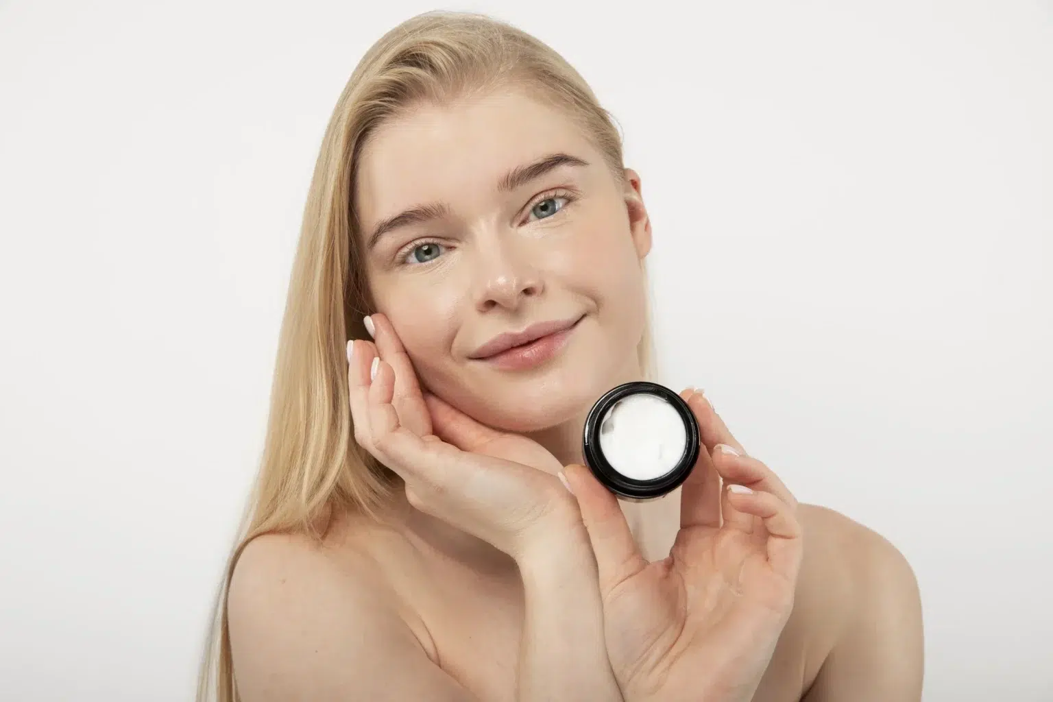 Kobieta z piękną skórą trzyma krem do twarzy wzmacniający mikrobiom skóry